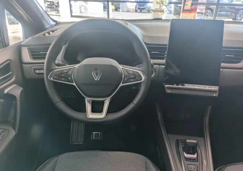 Vue intérieure frontale du tableau de bord du Renault Captur E-Tech gris cassiopée avec écran tactile vertical et volant multifonction.