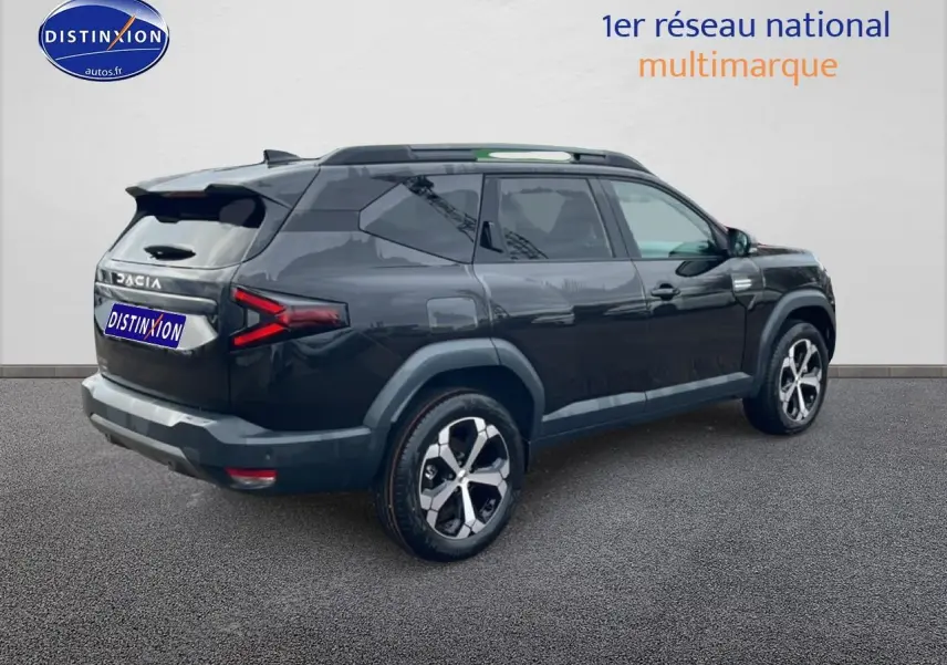 Vue 3/4 arrière droite du Dacia Bigster noir 2025 avec jantes alliage diamantées et barres de toit visibles.