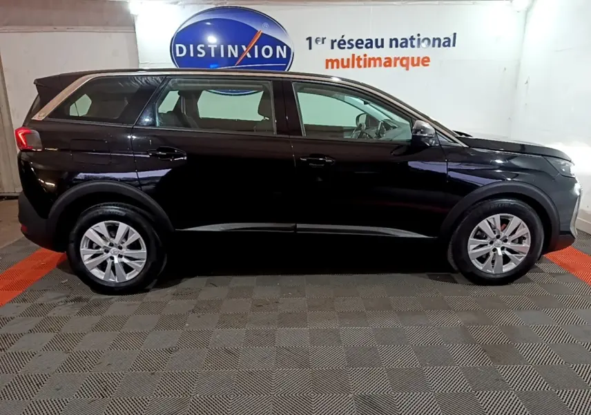 Peugeot 5008 noir vue de profil côté gauche, avec jantes alliage et feux arrière LED visibles en intérieur showroom.