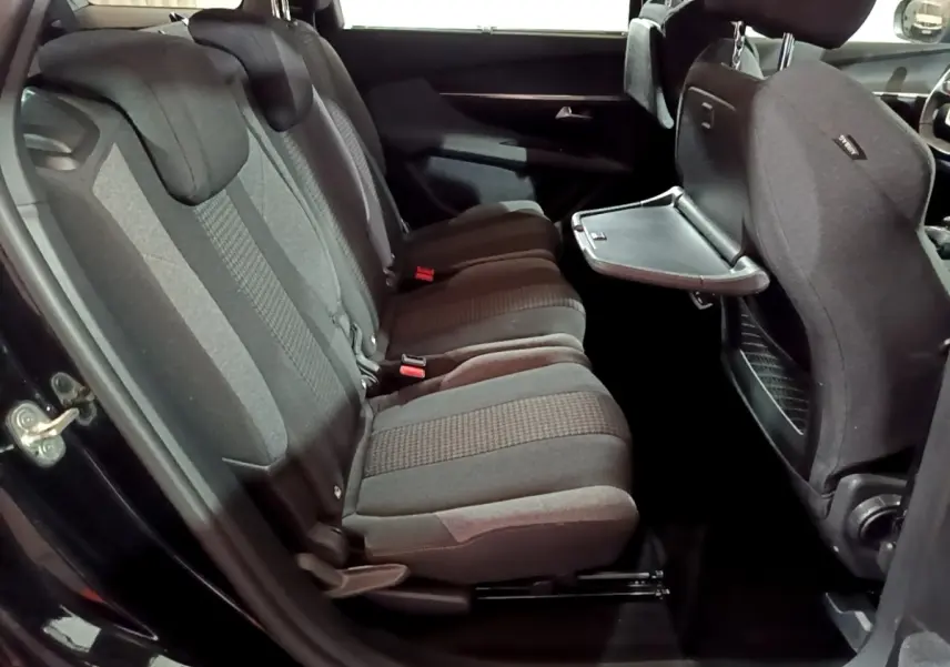 Vue intérieure côté gauche des sièges arrière noirs du Peugeot 5008 avec tablette rabattable sur le dossier avant.