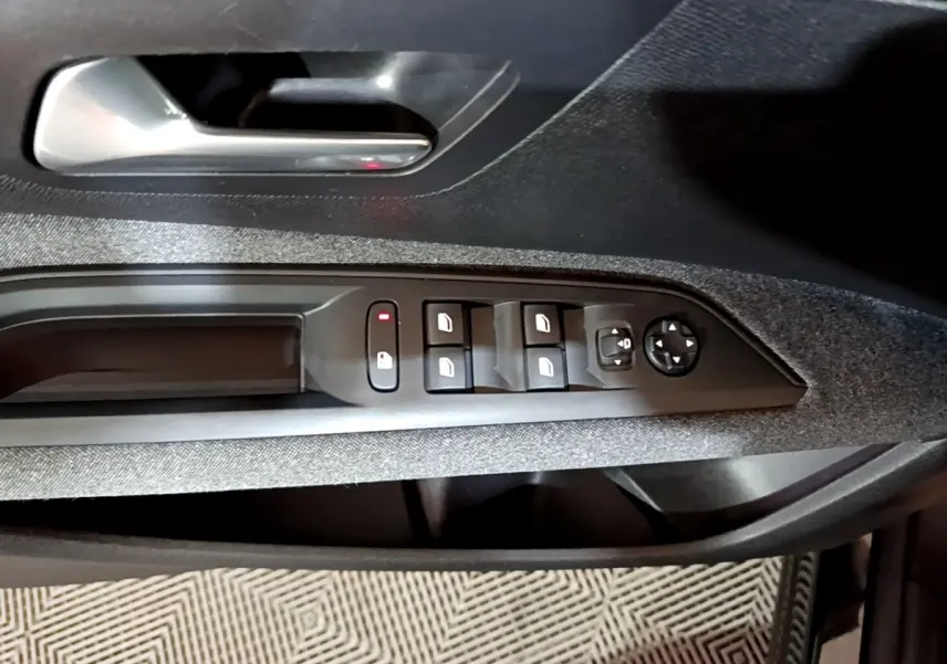 Vue rapprochée de la porte côté conducteur du Peugeot 5008 noir, montrant les commandes des vitres et rétroviseurs.