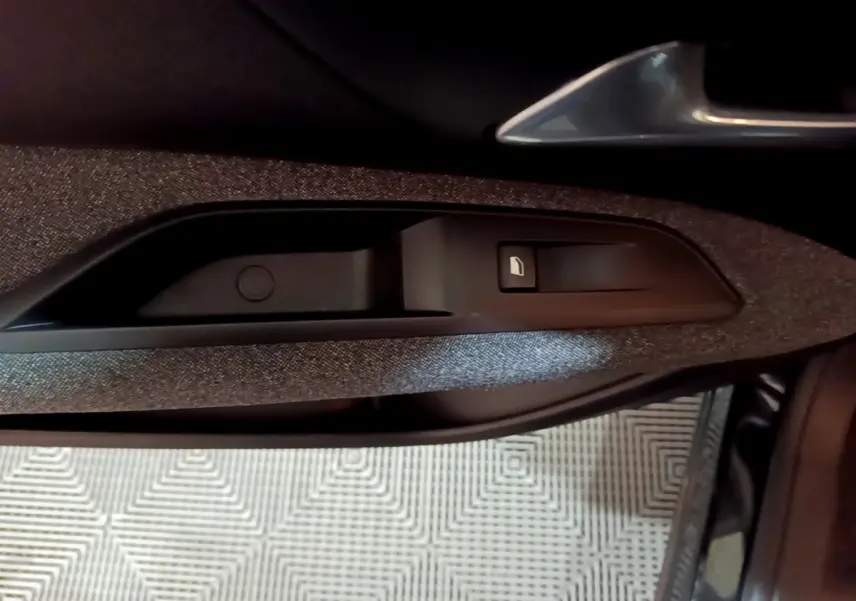 Détail de la commande de lève-vitre sur la porte côté conducteur d’un Peugeot 5008 noir, intérieur tissu gris.