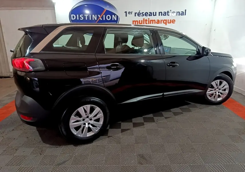 Peugeot 5008 noir vue de profil côté droit en intérieur avec jantes alliage et feux arrière LED allumés.