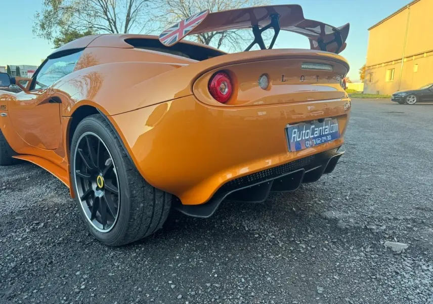 Vue 3/4 arrière droite de la Lotus Elise 3 Cup 250 orange avec jantes noires satinées et aileron arrière marqué du drapeau britannique.
