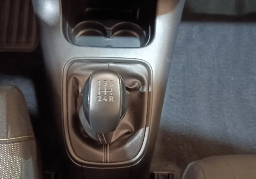 Vue plongeante sur la boîte manuelle noire de la Citroën C3 blanche, avec sièges tissu gris et surpiqûres jaunes visibles.