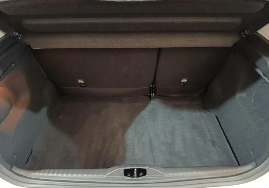 Coffre ouvert vu de l'arrière d'une Citroën C3 blanche, montrant un espace de chargement vide et tapis noir.