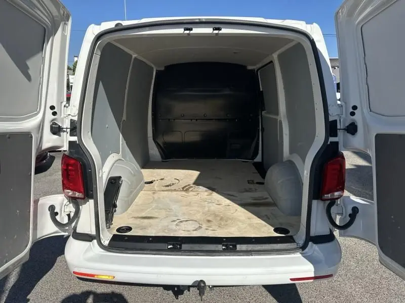 Vue arrière du Volkswagen Transporter blanc 2022 avec portes ouvertes montrant l'espace de chargement vide et spacieux.