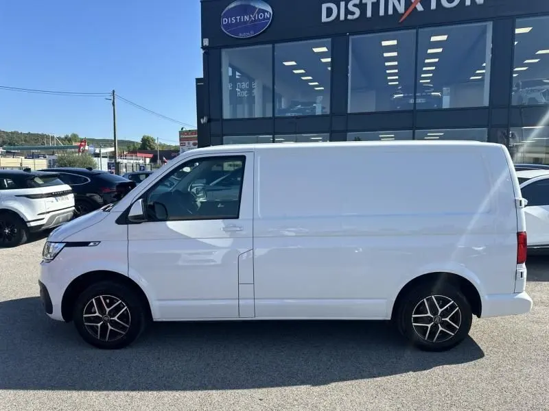 Profil côté gauche d'un Volkswagen Transporter blanc 2022, version 2.0 TDI Business avec jantes alliage noires.