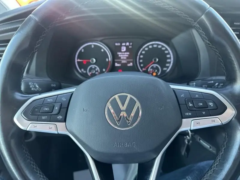 Vue rapprochée du volant noir du Volkswagen Transporter 2.0 TDI 150 Business 2022 avec tableau de bord numérique en arrière-plan.