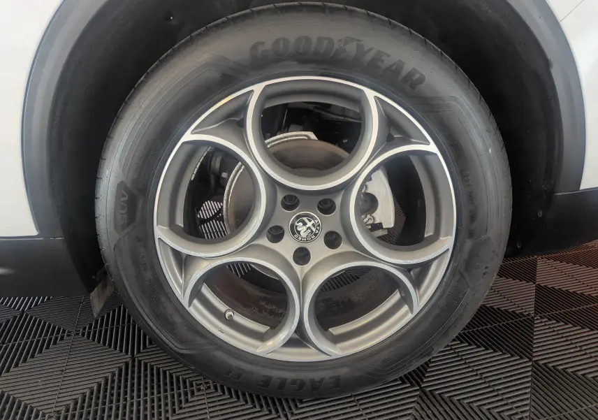 Gros plan sur la roue arrière droite d'un Alfa Romeo Stelvio blanc 2023, soulignant le pneu et l'arche de roue.