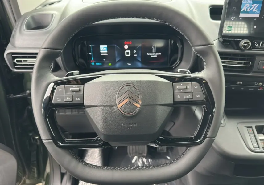 Vue rapprochée du volant noir du Citroën Berlingo 2025 avec commandes intégrées et tableau de bord numérique.