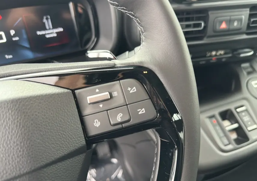Gros plan sur les commandes au volant du Citroën Berlingo 2025, finition BlueHDi 130 EAT8, intérieur noir moderne.