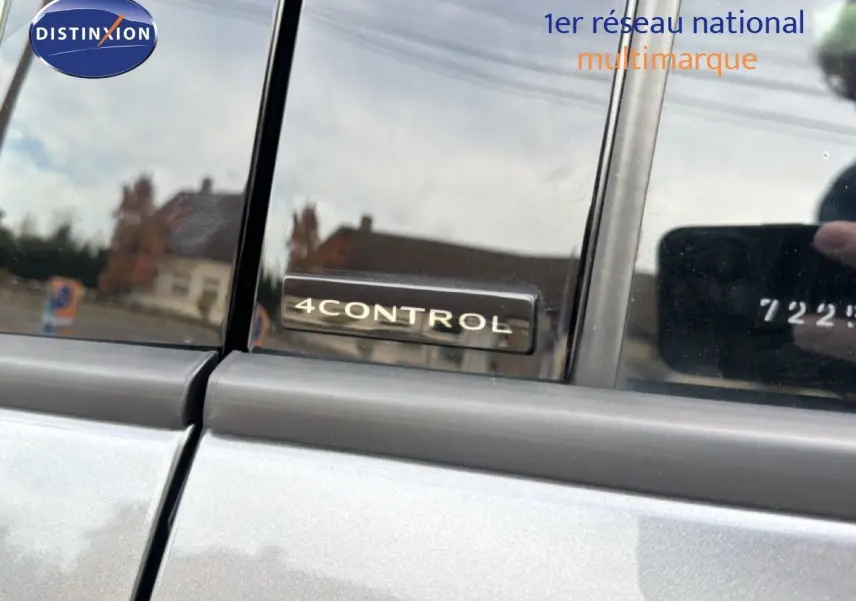 Gros plan sur l'insigne 4Control sur la porte arrière côté gauche d'un Renault Austral gris schiste avec toit noir.