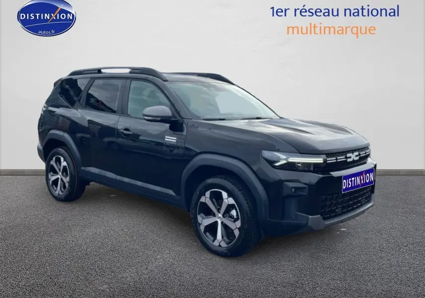 SUV Dacia Bigster noir en 3/4 avant droit avec jantes alliage diamantées et barres de toit visibles.
