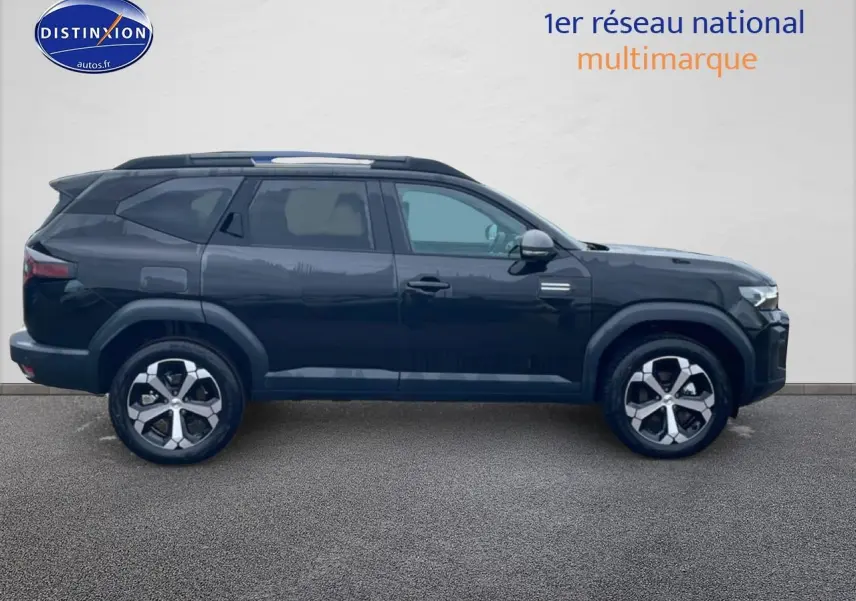 Profil droit du SUV Dacia Bigster noir 2025 avec jantes alliage diamantées et barres de toit visibles.