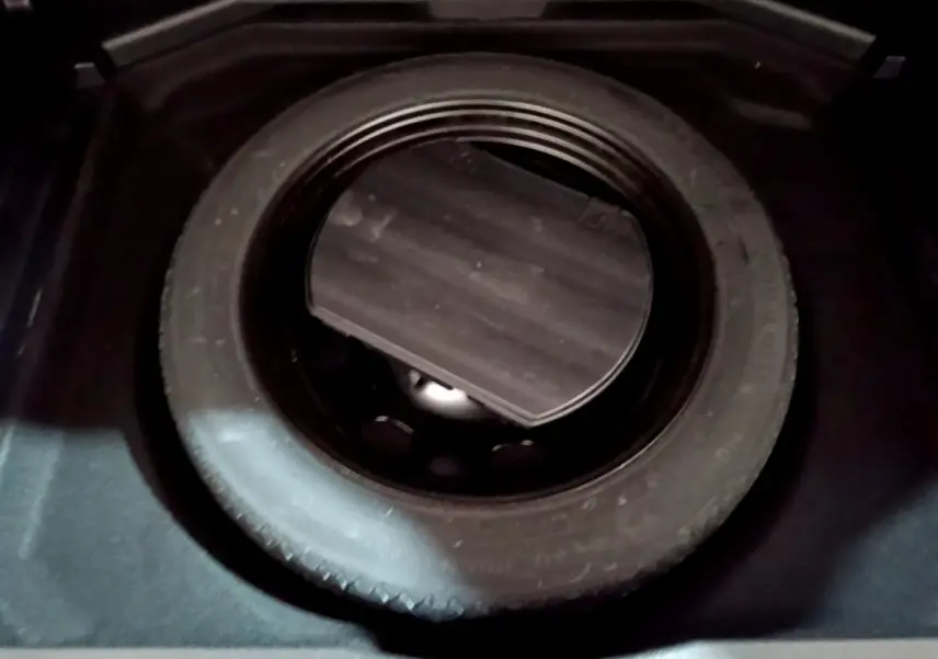 Gros plan sur la roue de secours noire dans le coffre d’un Peugeot 3008 gris clair, version Puretech 130 S&S.