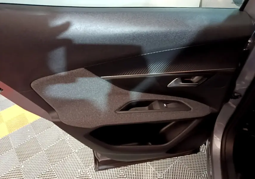 Vue intérieure du panneau de porte côté droit gris clair du Peugeot 3008, avec insert texturé et commande de lève-vitre.