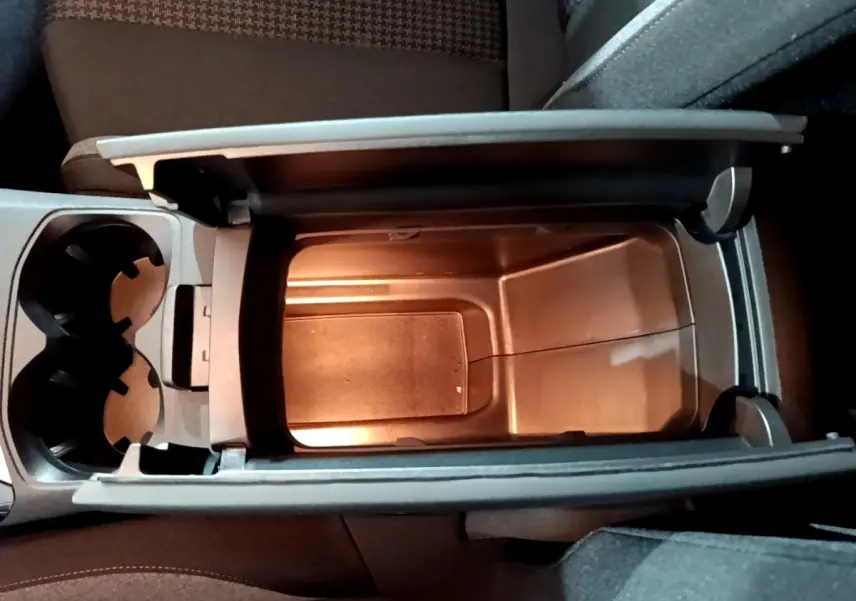 Vue plongeante sur le rangement central ouvert et porte-gobelets à l'intérieur du Peugeot 3008 gris clair de 2020.