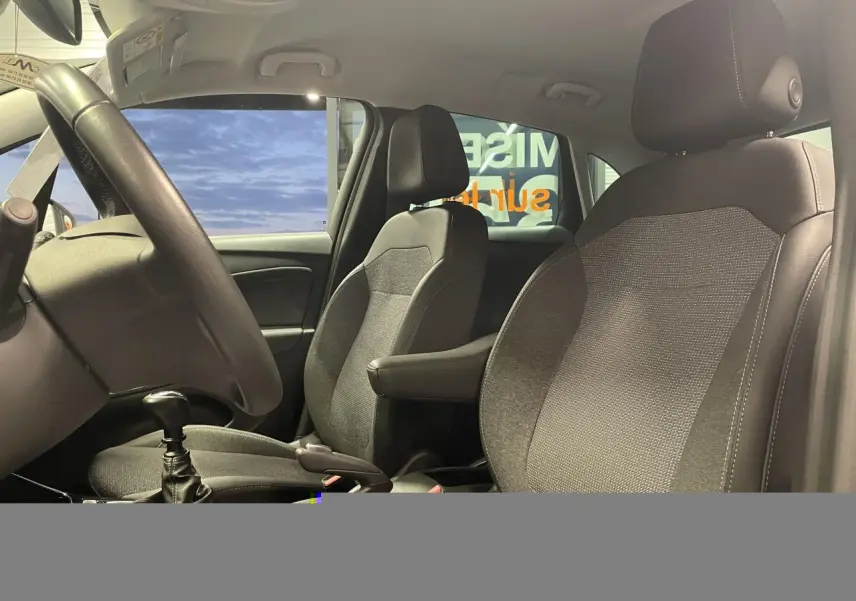 Vue intérieure côté conducteur de l’Opel Crossland 2024, sièges tissu noir avec accoudoir central et volant cuir.