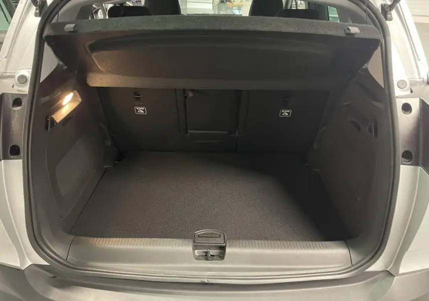 Coffre ouvert vu de l'arrière d'un Opel Crossland gris clair, montrant un espace de chargement propre et vide.