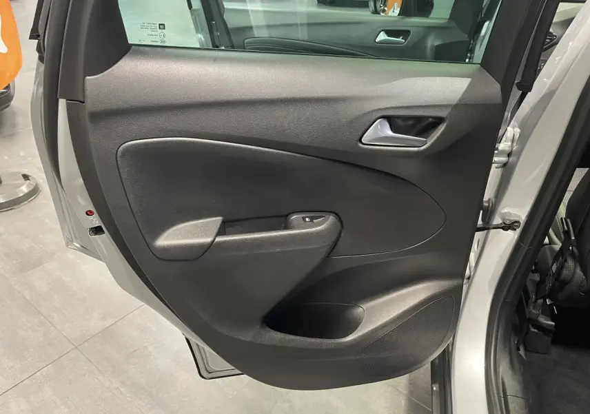 Porte arrière droite ouverte de l’Opel Crossland gris clair, montrant la garniture intérieure noire avec poignée et commande de vitre.