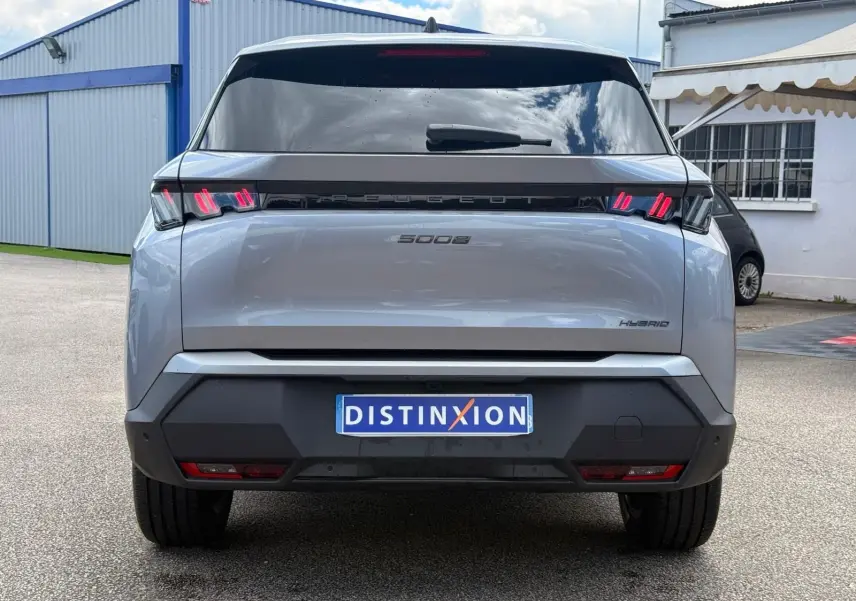 Vue arrière d'un Peugeot 5008 gris Artense hybride 2025 avec feux arrière LED distinctifs et plaque d'immatriculation Distinxion.