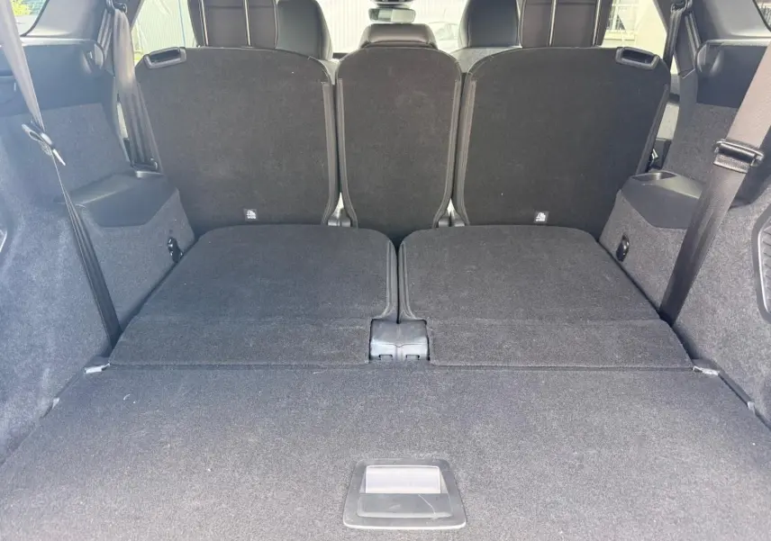 Vue arrière du coffre du Peugeot 5008 Hybrid 145 gris Artense avec sièges rabattus et espace de chargement plat.