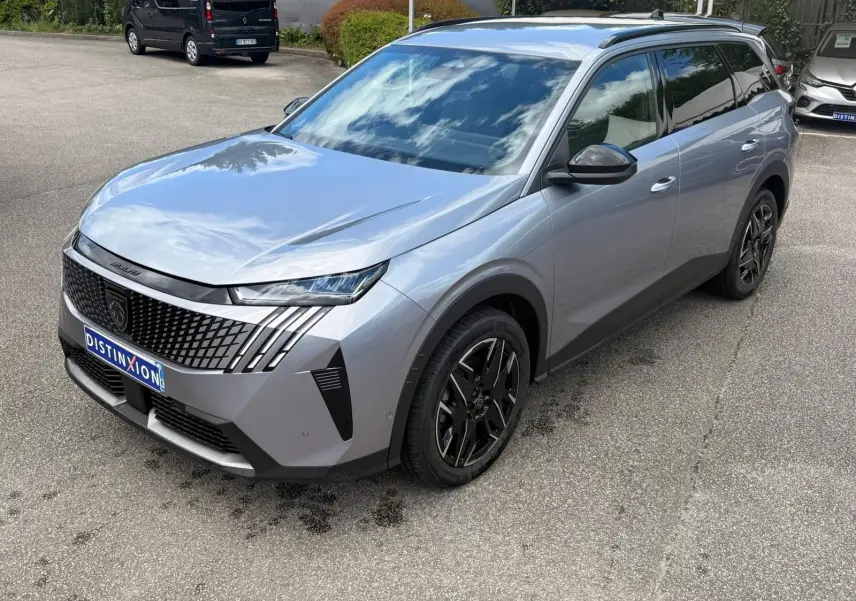 Peugeot 5008 Hybrid gris Artense vue 3/4 avant droit, avec calandre distinctive et jantes noires stylisées.