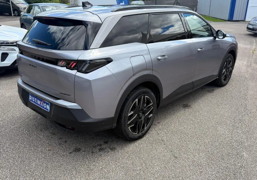 Vue 3/4 arrière droite du Peugeot 5008 Hybrid gris Artense avec vitres teintées et jantes noires distinctives.