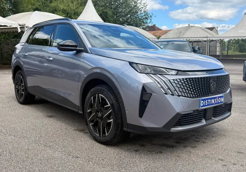 Peugeot 5008 Hybrid gris Artense en 3/4 avant droit, avec calandre noire et jantes alliage noires distinctives.