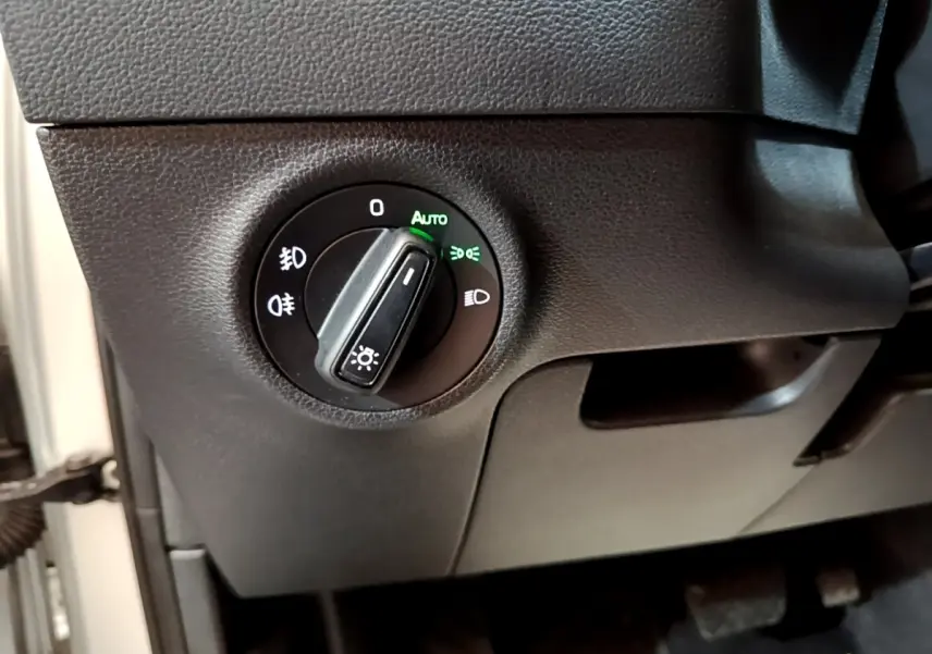 Gros plan sur le bouton de commande des phares du Skoda Karoq 2022, intérieur noir avec éclairage vert "Auto" activé.