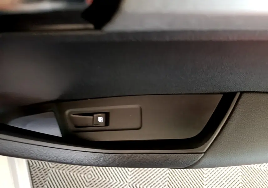 Détail de la commande de verrouillage des portes côté conducteur du Skoda Karoq gris clair, intérieur noir.