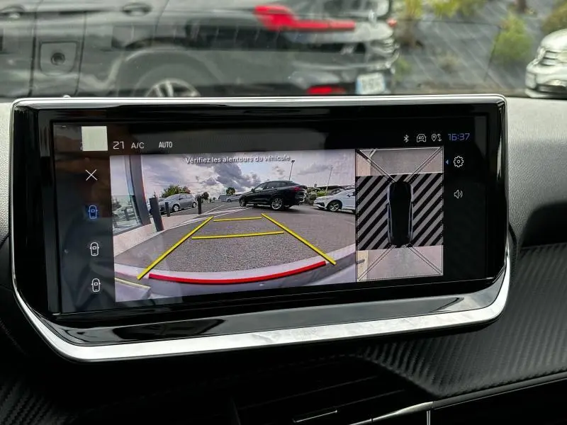 Écran tactile intérieur de la Peugeot 208 2024 montrant la caméra de recul avec vue arrière et top-down du véhicule noir.