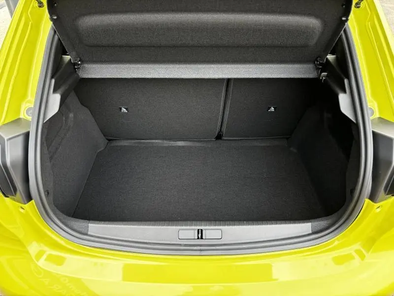 Coffre ouvert vu de l'arrière d'une Peugeot 208 2024 jaune Agueda, montrant un espace de chargement propre et spacieux.