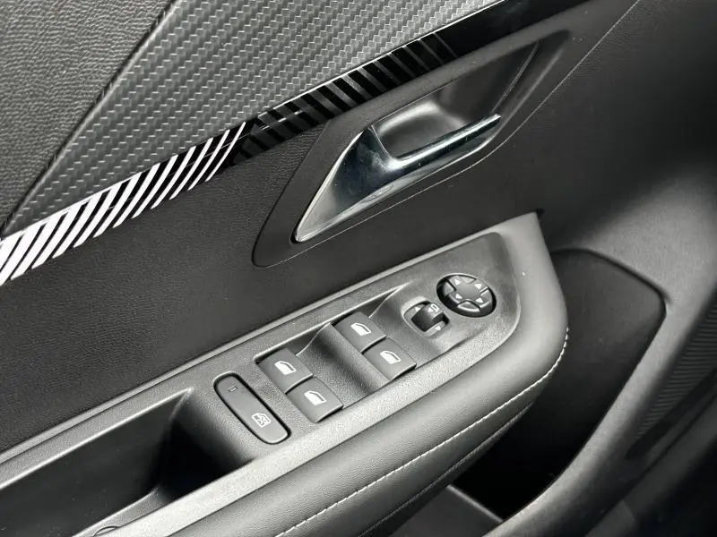 Vue rapprochée de la porte avant gauche noire de la Peugeot 208 2024 avec commandes électriques et poignée chrome.