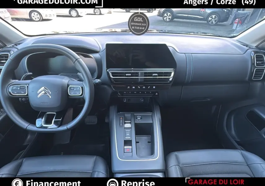 Vue intérieure avant du Citroën C5 Aircross noir, tableau de bord moderne avec écran tactile central et volant cuir multifonctions.