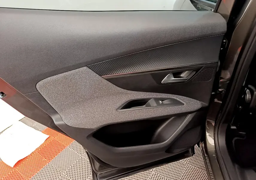 Vue intérieure de la porte arrière droite du Peugeot 3008 gris foncé, montrant les commandes de fenêtre et le revêtement textile.