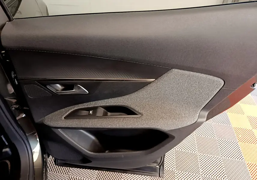Vue intérieure côté gauche de la porte avant d’un Peugeot 3008 gris foncé, avec habillage tissu et plastique noir.