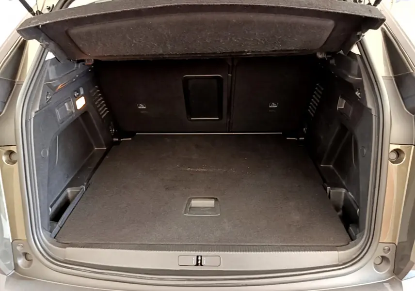 Coffre ouvert vu de l'arrière d'un Peugeot 3008 gris foncé, montrant un espace de chargement propre et spacieux.