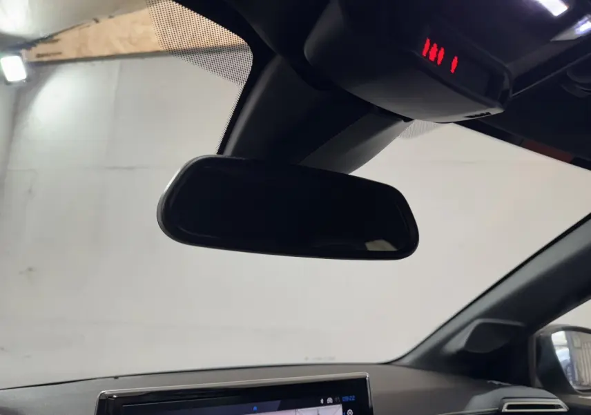 Vue intérieure centrée sur le rétroviseur et l’écran tactile du tableau de bord d’une Peugeot 208 Hybrid gris clair.