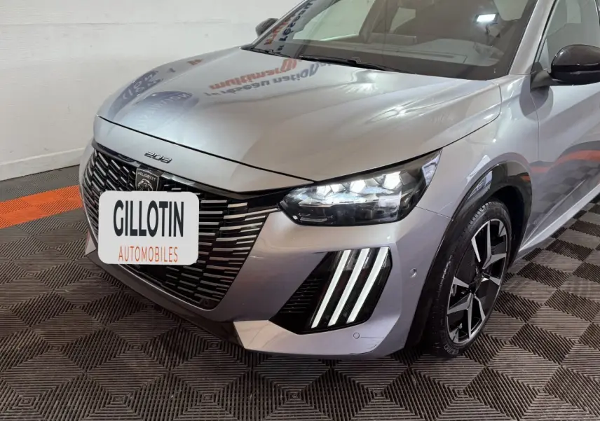 Vue 3/4 avant droit d'une Peugeot 208 Hybrid gris clair avec phares LED et signature lumineuse verticale distinctive.