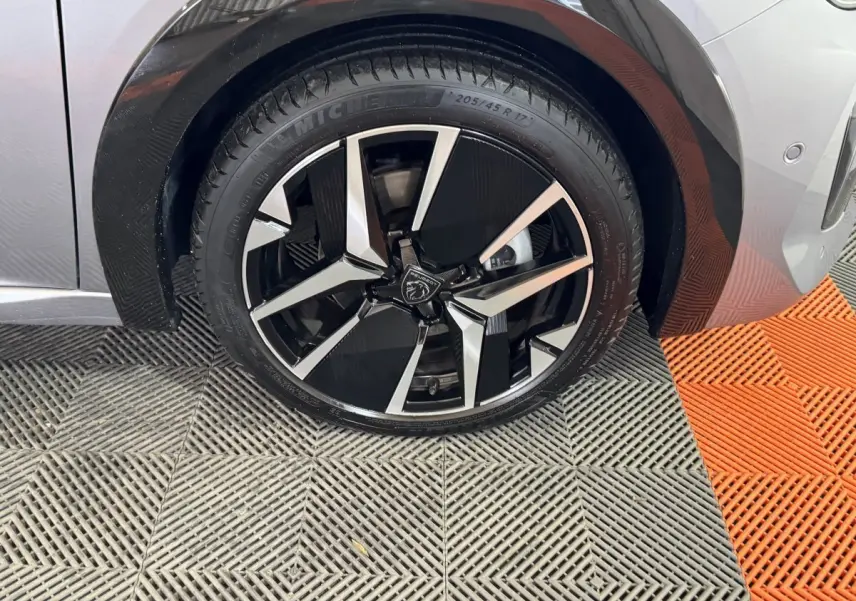 Gros plan sur la roue avant droite de la Peugeot 208 Hybrid 136 eDCS6 GT gris clair avec jante alliage noire et argent.