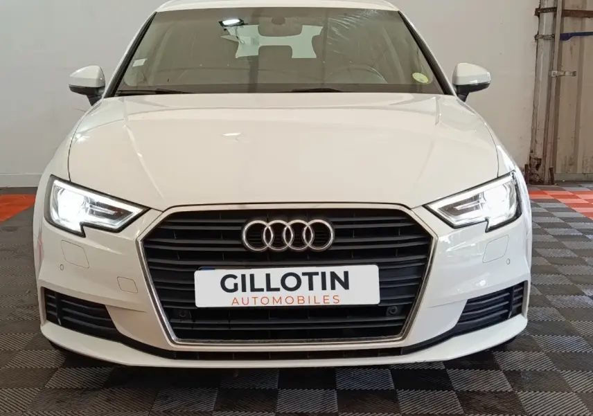 Vue avant d'une Audi A3 blanche de 2020 avec phares LED allumés et calandre noire distinctive.
