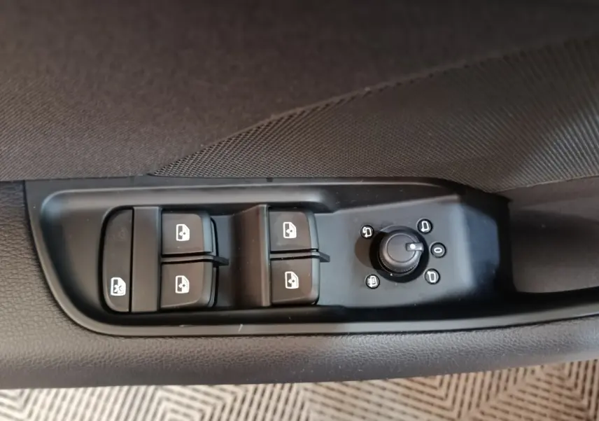 Gros plan sur les commandes de lève-vitres et réglage des rétroviseurs côté conducteur d'une Audi A3 blanche.