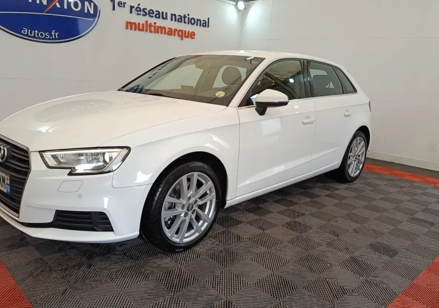 Audi A3 blanc vue 3/4 avant droit, avec jantes alliage et phares LED dans un showroom intérieur.