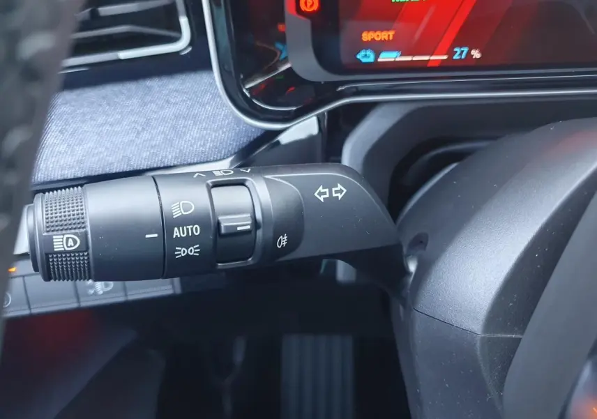 Gros plan sur la commande des clignotants et phares de la Renault R5 E-TECH 2026, tableau de bord numérique en arrière-plan.