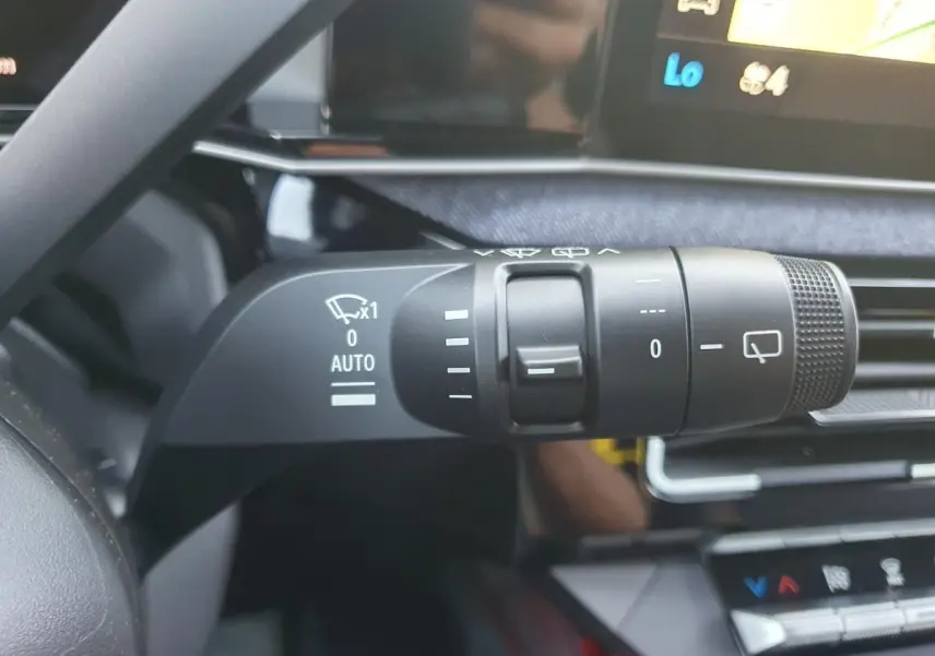 Gros plan sur la commande des essuie-glaces dans l’habitacle de la Renault R5 E-TECH jaune Pop, avec écran tactile en arrière-plan.