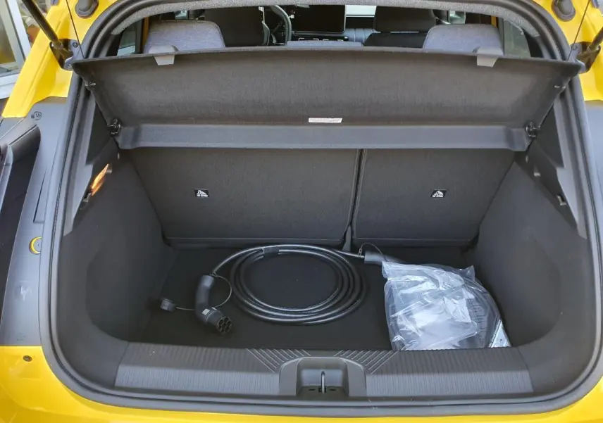 Coffre ouvert vu de l’arrière d’une Renault R5 E-Tech jaune Pop avec câble de recharge électrique visible.