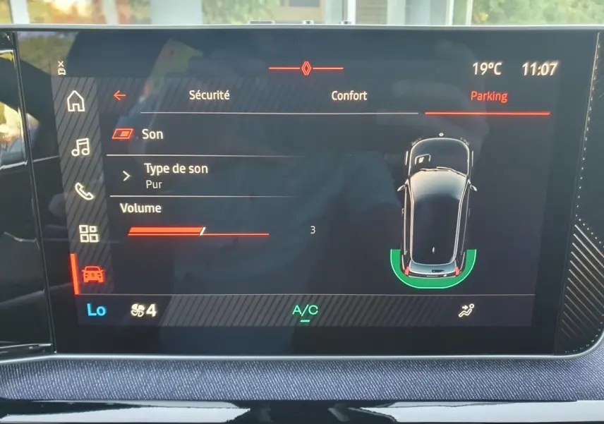 Écran tactile central de la Renault R5 E-Tech 2026 affichant l’aide au stationnement avec vue aérienne du véhicule.