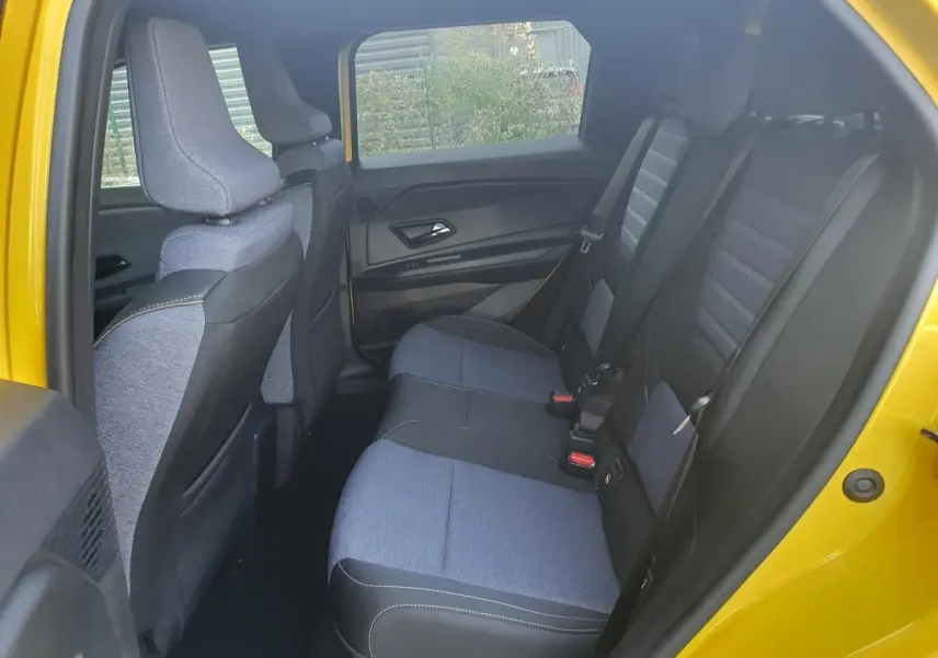 Vue intérieure arrière côté droit de la Renault R5 E-TECH jaune Pop, montrant les sièges arrière en tissu bicolore gris et noir.